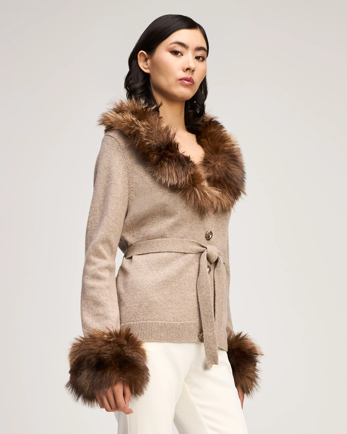 Full-length view of a model showcasing the Cinq à Sept Sandy Cardigan paired with white trousers and brown heels.