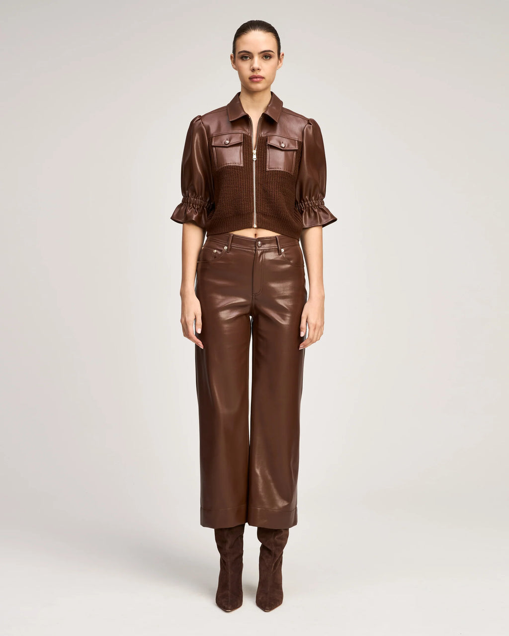 Model wearing the Cinq à Sept Joey Pant in Espresso brown vegan leather with high-rise waist and cropped wide leg.