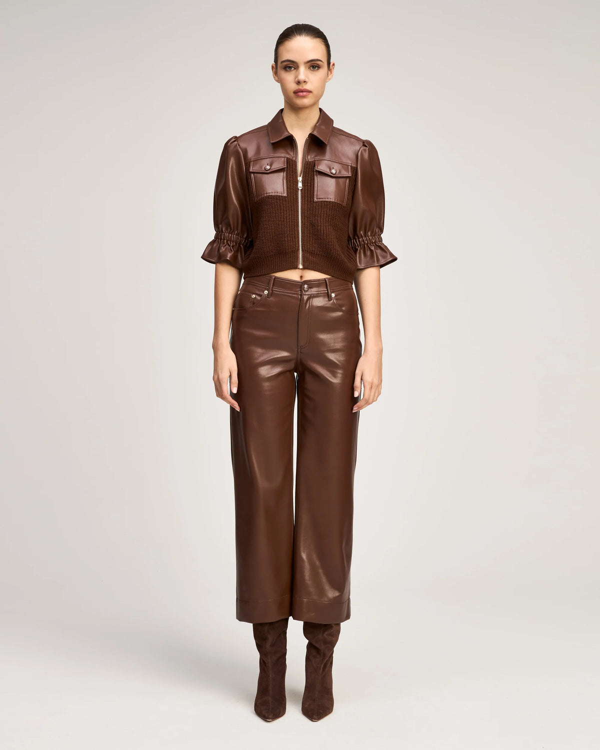 Model wearing the Cinq à Sept Joey Pant in Espresso brown vegan leather with high-rise waist and cropped wide leg.